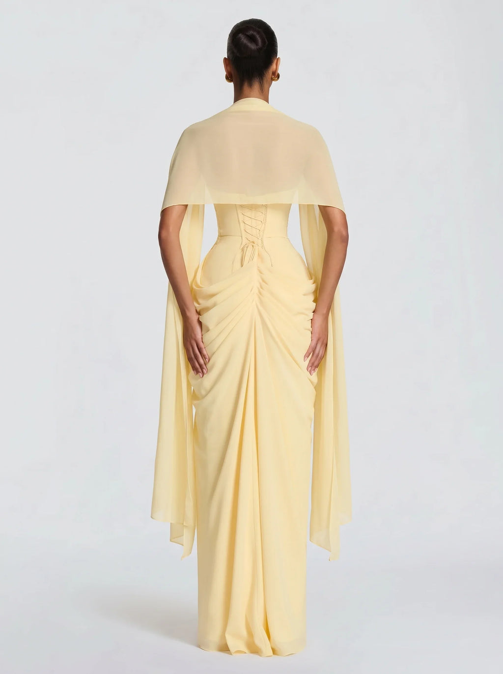 Mujer con estola de chifón amarillo Nora™ para una boda, vista de espalda