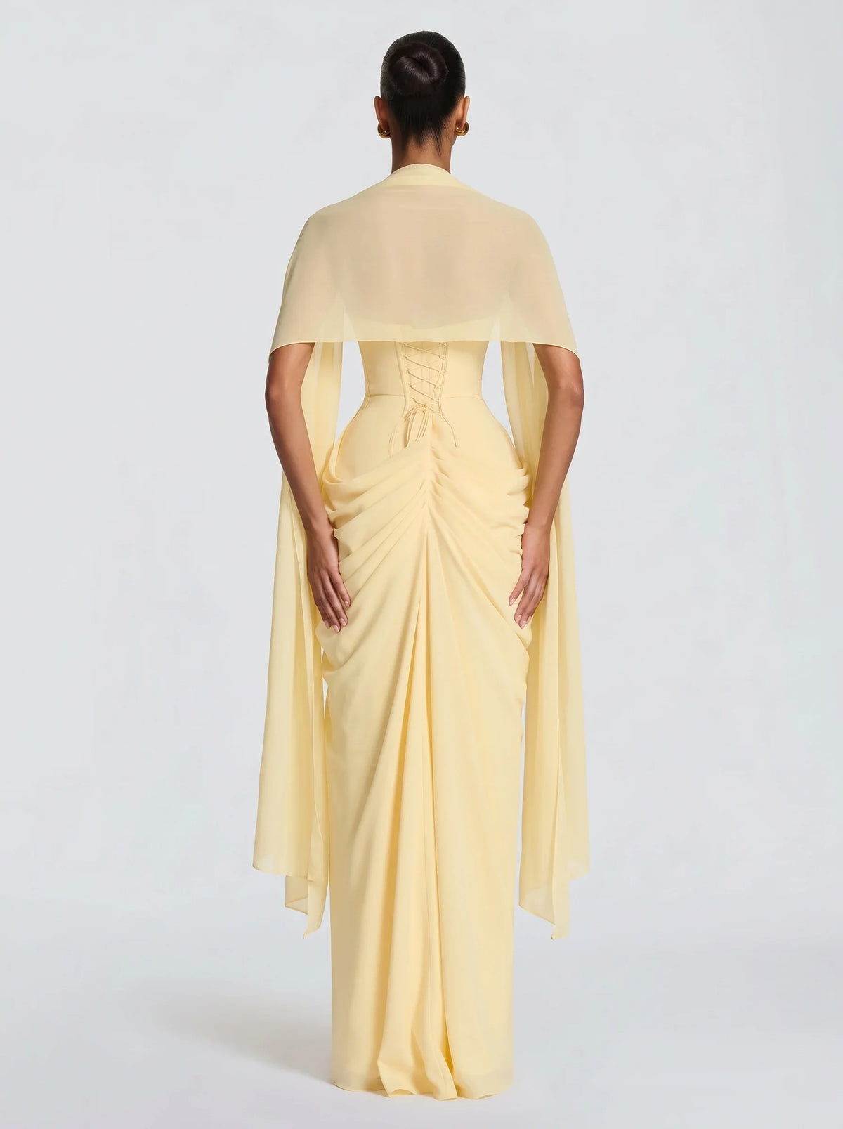 Mujer con estola de chifón amarillo Nora™ para una boda, vista de espalda